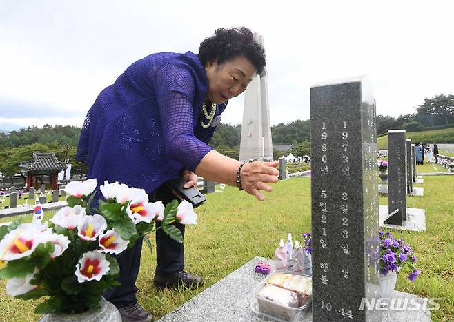 [광주=뉴시스] 김혜인 기자 = 18일 오전 5·18민주묘지 행방불명자 묘역에서 이창현군의 어머니가 아들의 사진을 만지고 있다. 2023.05.18. hyein0342@newsis.com