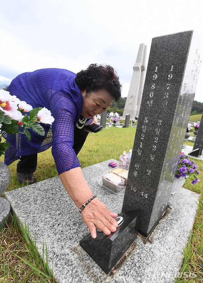 [광주=뉴시스] 김혜인 기자 = 18일 오전 국립 5·18민주묘지 행방불명자 묘역에서 이창현군의 어머니가 아들의 사진을 어루만지고 있다. 2023.05.18. hyein0342@newsis.com