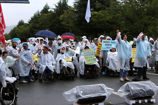 경남장애인차별철폐연대가 도청 정문 앞 도로에서 집회를 열고 있다. [사진=이세령 기자]