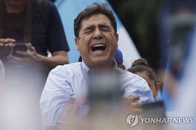과테말라 국가 부르는 카를로스 피네다 (과테말라시티 AP=연합뉴스) 다음 달 치러질 과테말라 대선에 출마했다가 후보 자격 일시 정지 처분을 받은 카를로스 피네다가 지난 20일(현지시간) 과테말라 수도 과테말라시티에 있는 헌법재판소에 항소장을 내고서 지지자들과 국가를 부르고 있다. 2023.5.22