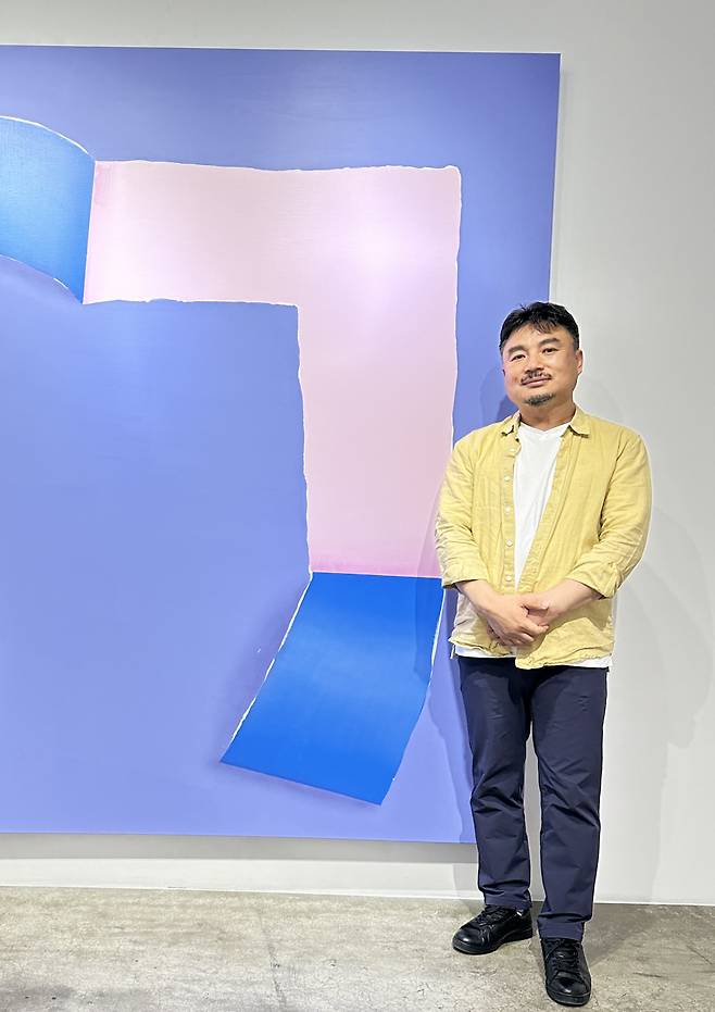 Kim Bo-seong poses for a photo with his painting "Gi-yeok" at Maru Art Center in Seoul. (Courtesy of the artist)