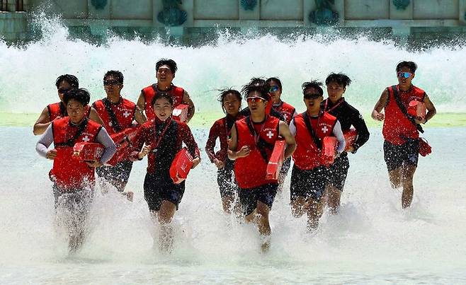 25일 경기 용인시 에버랜드 캐리비언 베이에서 야외 파도풀 개장에 앞서 인명구조훈련에 나선 수상안전요원들이 인공파도를 맞으며 체력훈련을 하고 있다.