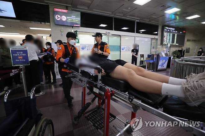 대구공항에서 실려나오는 학생들 (대구=연합뉴스) 윤관식 기자 = 26일 오후 대구국제공항에서 비상착륙한 비행기에서 몸에 이상이 있는 해당 비행기 탑승 학생들이 들것에 실려 나오고 있다. 2023.5.26 psik@yna.co.kr