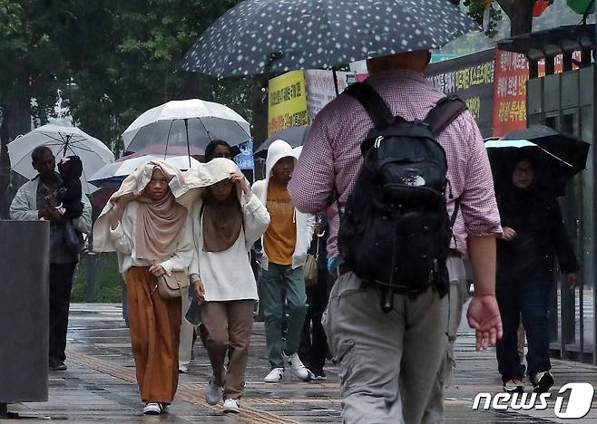 북상하는 기압골의 영향을 받아 수도권 등에 비가 내린 27일 오전 서울 중구 태평로 일대를 지나는 외국인들이 우산과 옷을 이용해 비를 피하고 있다. 2023.5.27/뉴스1 ⓒ News1 박정호 기자