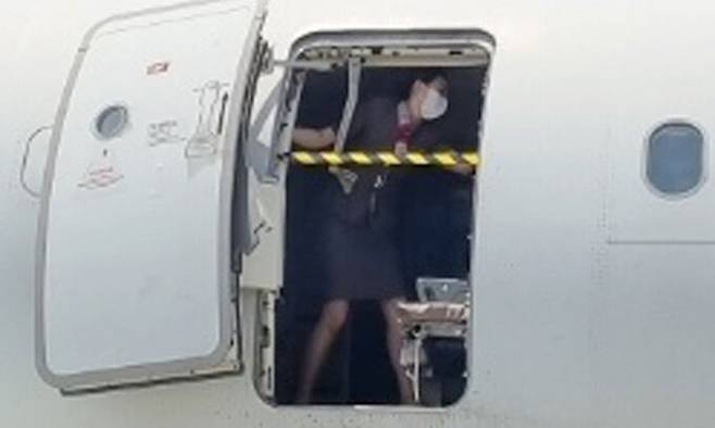 지난 26일 제주공항에서 출발해 대구공항에 비상구 출입문이 열린 채 착륙한 아시아나항공기에서 한 승무원이 문에 안전바를 설치한 뒤 두 팔을 벌려 막고 있다. 대구국제공항 관계자 제공