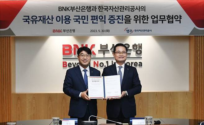 BNK부산은행 방성빈 은행장(왼쪽)과 한국자산관리공사 권남주 사장이 업무협약서를 들고 기념사진을 찍고 있다./제공=BNK부산은행