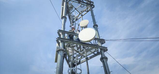 SK텔레콤 직원들이 도서 지역에 설치된 5G 마이크로웨이브 통신 장비를 점검하는 모습. /SKT