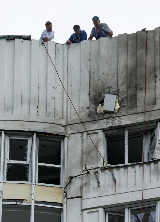30일 러시아 수도 모스크바에 가해진 드론(무인기) 공격으로 파손된 건물 옥상에서 관계자들이 피해 상황을 살펴보고 있다.  로이터 연합뉴스