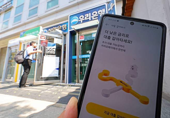 금융권의 온라인·원스톱 대환대출 플랫폼이 시행된 31일 오후 서울 시내에 설치된 시중은행들의 ATM기와 카카오페이 대출 비교 서비스 '대출 갈아타기' 화면 모습. 이날부터 소비자는 대출 비교 플랫폼, 주요 금융회사 등의 스마트폰 앱을 통해 기존에 받은 신용대출을 더 유리한 조건으로 한 번에 갈아탈 수 있다. [연합]