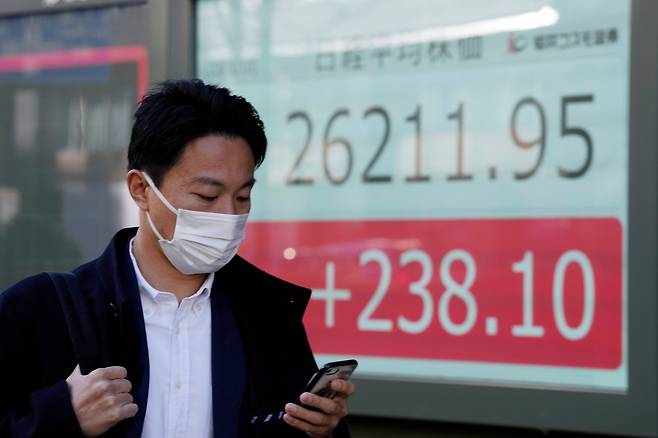 마스크를 착용한 한 일본 도쿄 시민이 10일 닛케이225지수를 보여주는 증권사 전광판 앞을 지나가고 있다. /도쿄AP 연합뉴스