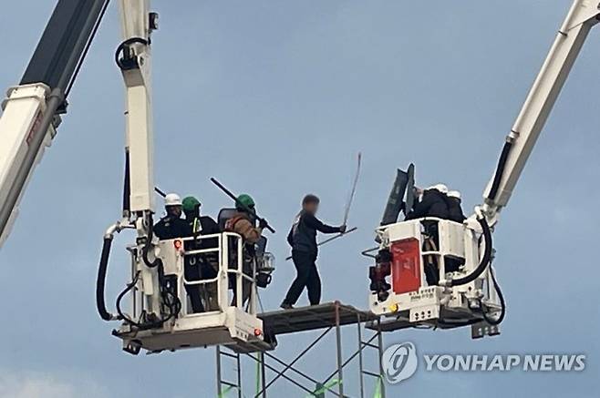 지난 달 31일 오전 전남 광양시 금호동 포스코 광양제철소 인근 도로에서 높이 7ｍ 망루를 설치해 고공농성을 벌인 한국노총 금속노련 간부가 체포에 나선 경찰관에게 막대를 휘두르며 저항하고 있다. 연합뉴스