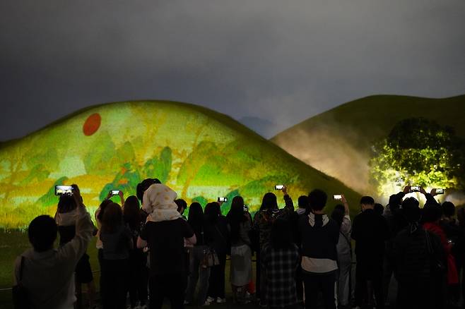 Spectators enjoy media art at Daereungwon in Gyeongju, North Gyeongsang Province, Tuesday. (Lee Si-jin/The Korea Herald)