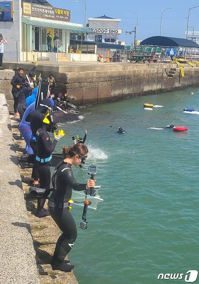 지난 3일 제주시 우도에서 열린 '세상에 이런트립' 참가자들이 해양정화활동을 위해 물 속으로 뛰어들고 있다.(제주관광공사 제공)/뉴스1