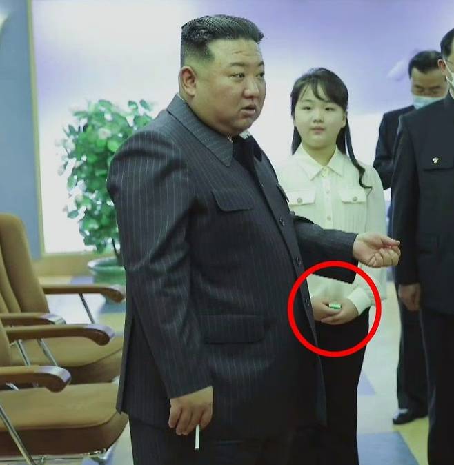 북한 김정은이 지난 4월 18일 국가우주개발국을 방문해 관계자들에게 지시하고 있다. 담배를 들고 있는 김정은 옆에 그의 딸 김주애(10)가 두 손으로 성냥갑(빨간 원)을 들고 있다. /조선중앙TV 뉴시스