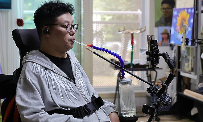 임 화가가 휴식을 취하며 특수 제작된 물통으로 물을 먹고 있다.