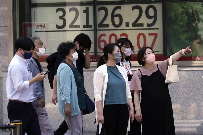 5일 일본 도쿄 증권사 증시 전광판 앞을 시민들이 지나고 있다. 일본 정부는 경제 부문 여성 활약 촉진 방안을 조만간 마련할 방침이다. 도쿄=AP 뉴시스