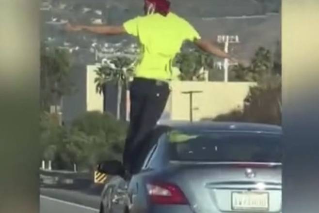 지난 4일(현지 시각) 미국 캘리포니아주 고속도로에서 한 남성이 주행하고 있는 차량의 창틀에 발을 딛고 서 있는 모습. / KTLA