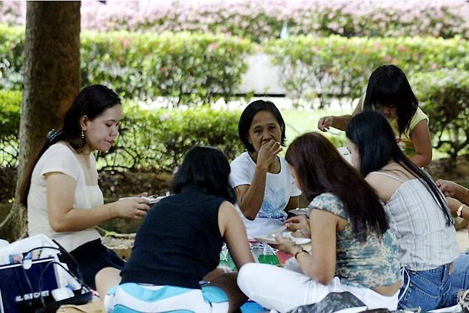 외국인 가사노동자들이 싱가포르의 한 공원에서 나들이를 즐기고 있다. AFP 사진, 사우스차이나 모닝포스트 화면 갈무리