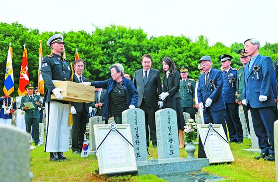 President Yoon Suk Yeol and first lady Kim Keon-hee, center, attend a burial ceremony for Kim Bong-hak, a late Army private first class who was killed in action during the 1950-53 Korean War whose remains were identified earlier this year, and his younger brother, Kim Seong-hak, also killed during the war, ahead of a ceremony to mark the 68th Memorial Day at Seoul National Cemetery on Tuesday. [PRESIDENTIAL OFFICE]