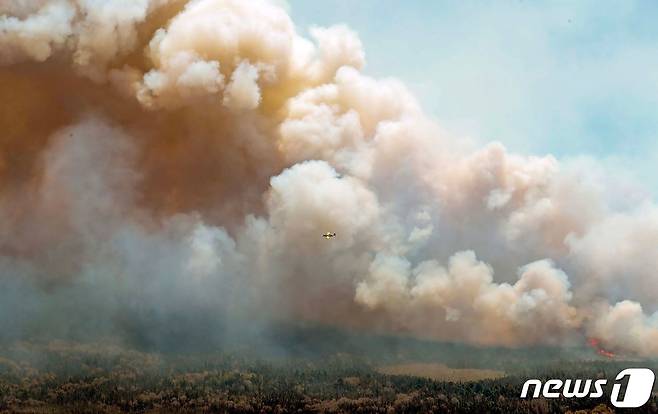 31일(현지시간) 캐나다 서버브 카운티에 있는 배링턴 레이크에서 대형 산불이 발생해 솟아오르는 연기 속에서 소방 헬기가 진화 작업을 하고 있다. 2023.6.2 ⓒ AFP=뉴스1 ⓒ News1 우동명 기자