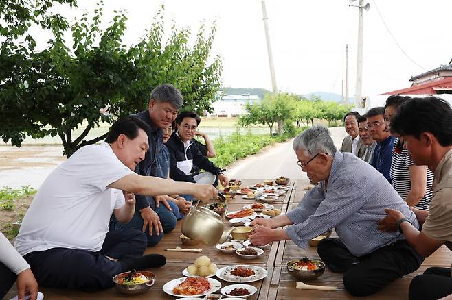 [서울=뉴시스] 윤석열 대통령이 7일 충남 부여군 임천면 꿈에영농조합법인을 방문해 모내기를 마친 뒤 주민들과 새참을 먹고 있다. (사진=대통령실 제공) 2023.06.07. photo@newsis.com *재판매 및 DB 금지