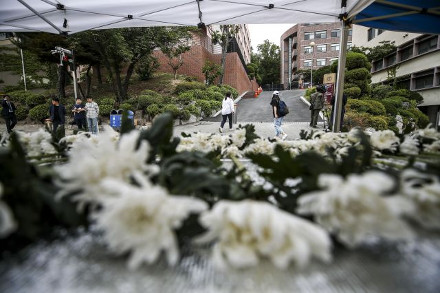 지난 5일 동덕여대 캠퍼스 안에서 등교하던 대학생이 언덕길에서 내려오던 쓰레기 수거용 화물차에 치여 뇌사 상태에 빠진 뒤 이틀 만에 숨진 가운데 8일 오후 서울 성북구 동덕여자대학교에 마련된 추모공간 뒤로 사고현장이 보이고 있다. 뉴시스