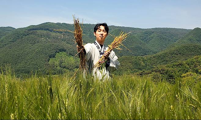 강원도 영월에서 보리 빨대를 만드는 ‘비어스’ 김인수 대표가 보리밭 앞에서 빨대 제작을 위해 건조한 보릿대를 들고 포즈를 취하고 있다.