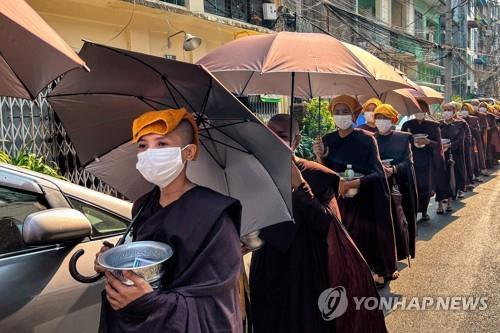 폭염으로 인해 머리에 수건과 우산을 쓴 미얀마인들 [AFP=연합뉴스 자료사진. 재판매 및 DB 금지]