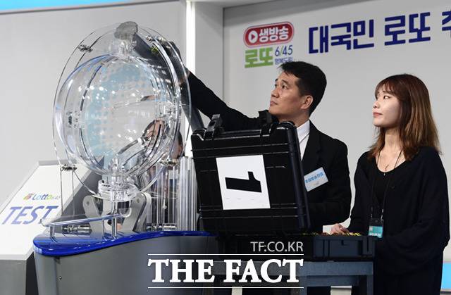 참관인 이나연 씨(오른쪽)가 이날 쓰일 추첨볼 1번 세트의 45개 추첨볼 내 RFID칩이 제대로 작동하는지 무작위로 꺼낸 공을 직원에게 건네 확인하고 있다. RFID 칩은 추첨기에서 공이 뽑혔을 때 자동으로 전자기기가 이 공의 번호를 인식할 수 있게 하는 장치다.