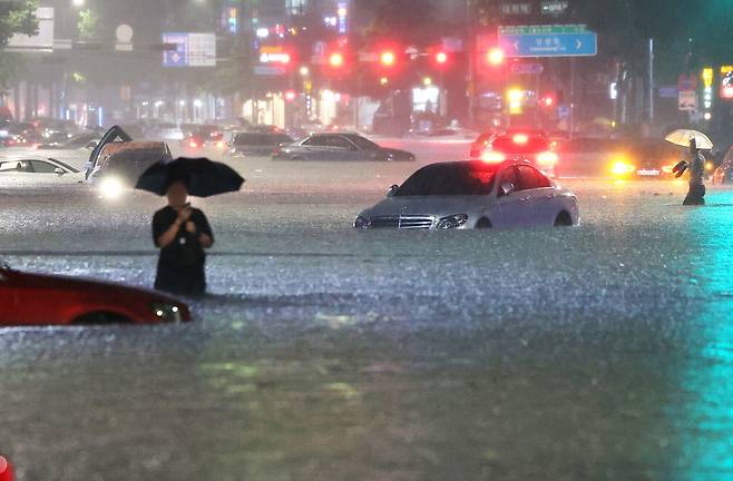 지난해 8월 8일 중부지방 집중호우로 서울 강남구 대치역 인근 도로가 물에 잠기자 운전자들이 침수된 차를 버리고 대피하고 있다.  연합뉴스