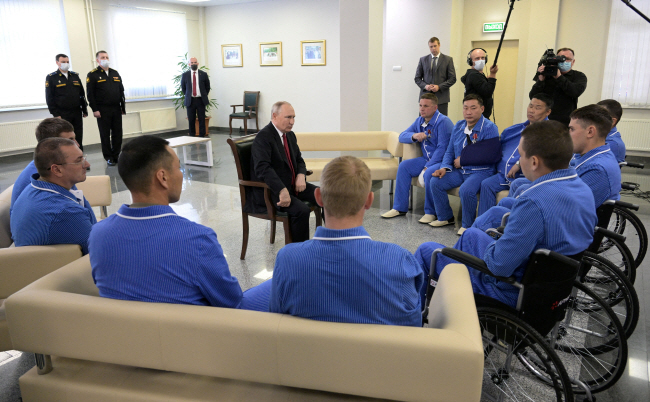 블라디미르 푸틴(가운데) 러시아 대통령이 12일 모스크바의 군 병원에서 부상 장병들과 만나 대화하고 있다.  로이터 연합뉴스