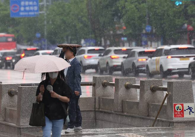 소나기가 내린 14일 오후 서울시내에서 한 시민이 가방으로 비를 피하고 있다. 연합뉴스