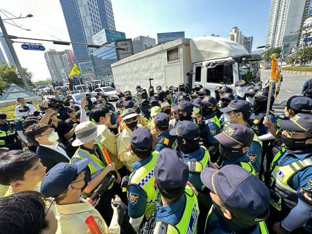 17일 오전 대구 중구 반월당역 인근에서 퀴어문화축제 측 무대차량 진입을 위해 교통 정리에 나선 경찰관들과 이를 막으려는 대구시 공무원들이 대치하고 있다. 경찰 뒤쪽으로 무대차량이 진입하고 있다. 연합뉴스