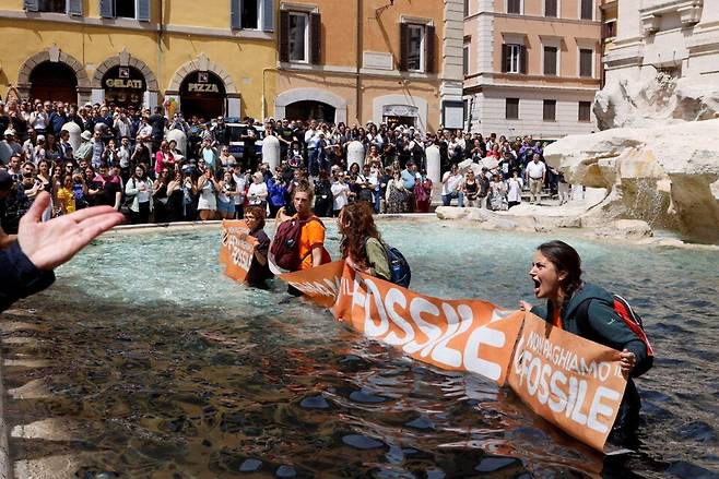 환경단체 울티마 제네라치오네(마지막 세대) 기후활동가들이 2023년 5월21일 이탈리아 로마의 유명 관광지 트레비분수에 식물성 먹물을 뿌린 뒤 화석연료에 공적 보조금 지급을 중단하라는 시위를 벌이고 있다. 연합뉴스