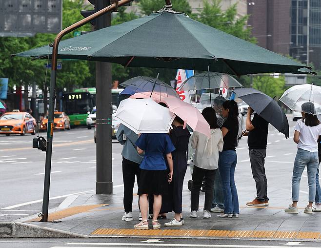 비가 내린 20일 오후 우산을 쓴 시민들이 서울 종로구 광화문광장 인근 그늘막에서 비를 피하고 있다. 연합뉴스