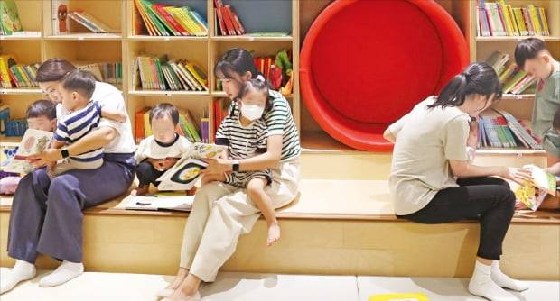 어린이집 교사가 13일 경기 성남시 HD현대 글로벌R&D센터 내 드림보트에서 유아반(만 3~5세) 어린이들에게 책을 읽어주고 있다. 오른쪽 사진은 오후 5시 저녁 식사 중인 유아반 아이들. 강은구/김범준 기자