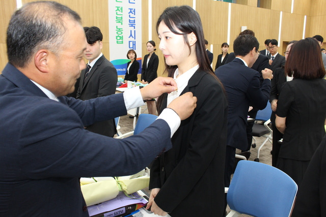 김영일 전북농협본부장(왼쪽)이 한 농·축협 신입 직원에게 농협 배지를 달아주고 있다.