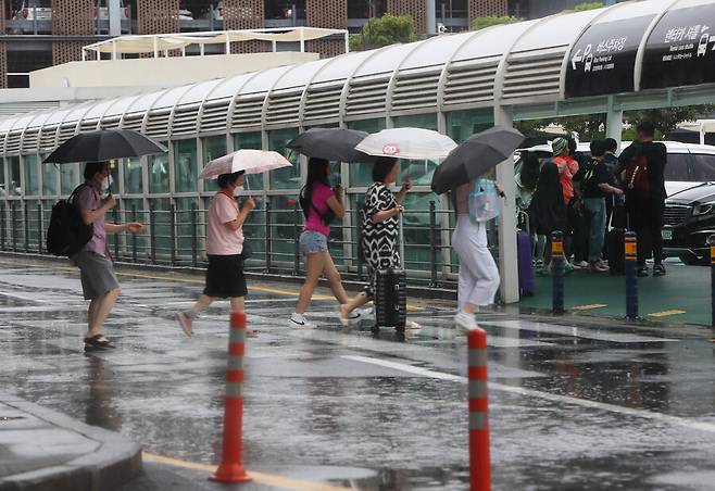 25일 제주국제공항에 비가 쏟아지는 가운데 관광객들이 이동하고 있다. 연합뉴스