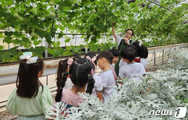 계룡농업기술센터 내 과학영농시설에 조성된 ‘주렁주렁 박터널’에서 어린이들이  관계자의 설명을 듣고 있다. (계룡시 제공) /뉴스1