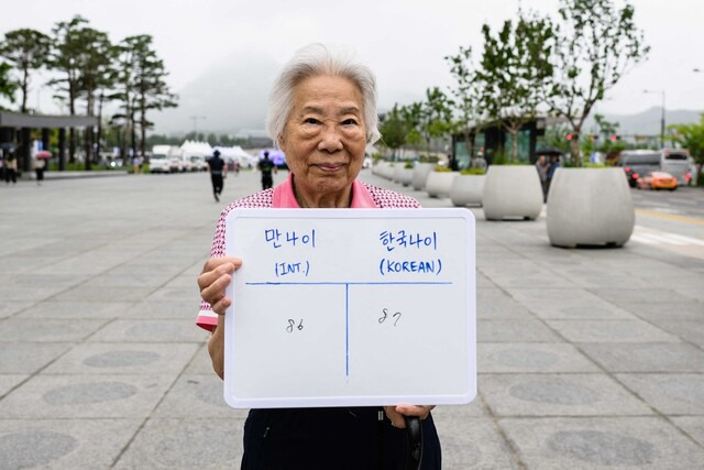 ‘만 나이 통일법’이 시행되기 전인 지난 21일 한 여성이 만 나이인 86살과 한국 나이인 87살을 보여주는 화이트보드를 들고 포즈를 취하고 있다. AFP 연합뉴스