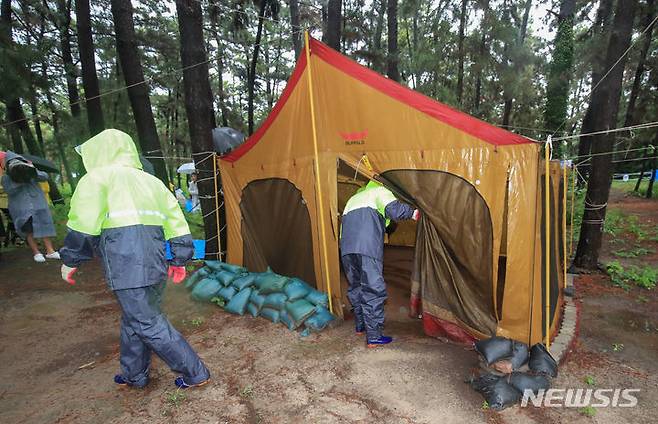 [제주=뉴시스] 우장호 기자 = 장맛비가 내리는 30일 오후 제주시 한림읍 금능해수욕장 인근 야영장에서 제주시청 관계자들이 '알박기' 텐트를 철거하고 있다. 제주시는 시민과 관광객이 효율적으로 해수욕장과 야영장을 사용할 수 있도록 7월1일부터 8월31일까지 협재·금능 청년회에 한시적으로 운영을 위탁해 유료화할 계획이다. 2023.06.30. woo1223@newsis.com