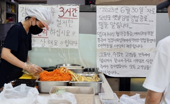 8일 전북 전주시 완산구 삼천동 오선모김밥에서 오선모 사장의 자녀가 김밥을 말고 있다. 가게 한 쪽에 손 글씨로 쓴 “그동안 전국에서 멀리까지 찾아주시고 너무 많은 사랑을 주셔서 감사합니다. 더 이상 영업 운영이 어려워 대단히 죄송합니다”라는 안내문이 붙어있다.연합뉴스