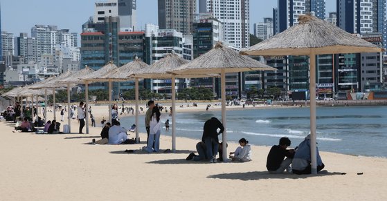 지난 5월 1일 부산 수영구 광안리해수욕장 백사장에 설치된 파라솔 아래에서 시민들이 바다를 보며 더위를 식히고 있다. 송봉근 기자