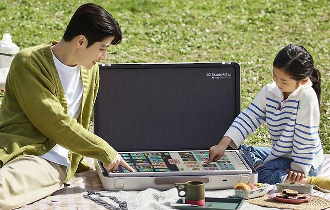 LG전자 모델들이 야외에서 이동형 스크린 ‘LG 스탠바이미 고’의 테이블 모드를 활용해 보드게임을 즐기고 있다. LG전자 제공