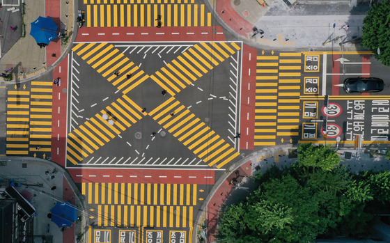 Thicker, more vivid yellow lines printed at a crosswalk in front of Gugal Elementary School in Yongin, Gyeonggi, on Monday. Newly reformed traffic regulations goes into effect Tuesday with crosswalks in front of school zones painted in yellow. The move aims to increase driver awareness and prevent accidents involving children. Police say in a tree-month trial in 12 school zones in seven areas across the country, 89 percent of drivers said the yellow crosswalks made them more aware, while 60 percent said they followed the rules more, including stopping at crosswalks. [YONHAP]