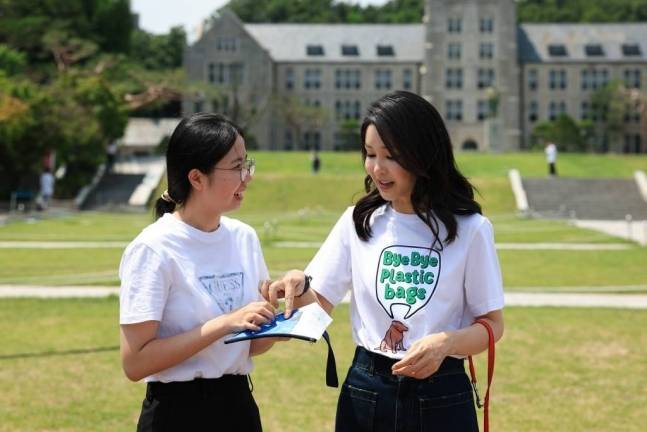 윤석열 대통령 부인 김건희 여사(오른쪽)가 지난달 5일 서울 성북구 고려대&nbsp;중앙광장에 마련된 바이바이플라스틱 캠페인 포토월을 찾은 학생에게 홍보 물품을 전달하고 있다. 대통령실 제공