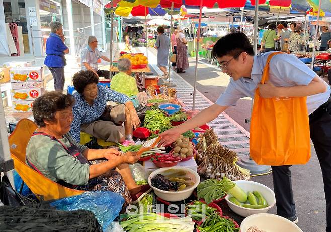 지난 3일 양평 물맑은시장에서 경상원 임직원들이 시장 상인들에게 비닐봉투 대신 사용할 다회용 장바구니를 나눠주고 있다.(사진=경기도시장상권진흥원)