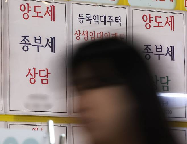 지난 6월 26일 양도세 상담 문구가 적힌 서울 잠실 공인중개사무소 앞을 시민이 지나고 있다. /연합뉴스