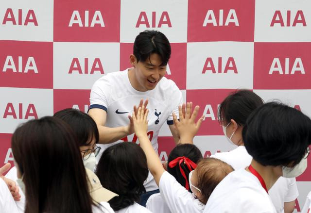 손흥민이 4일 서울 동대문구 글로벌지식협력단지 야외 잔디에서 열린 AIA 생명 ‘손별 모아 위시’ 캠페인 행사에서 소아암 환아들과 하이파이브를 하며 웃고 있다. 뉴시스