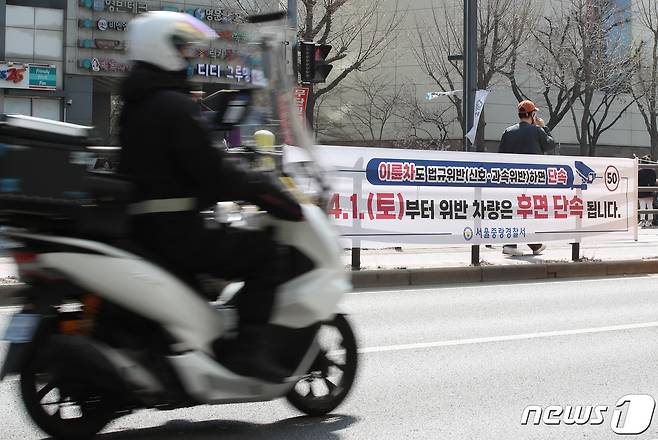 지난 3월 30일 오후 서울 중랑구 망우로 버스중앙차로에 설치된 후면 단속 안내 현수막 앞으로 오토바이가 지나가고 있다. 2023.3.30/뉴스1 ⓒ News1 박정호 기자